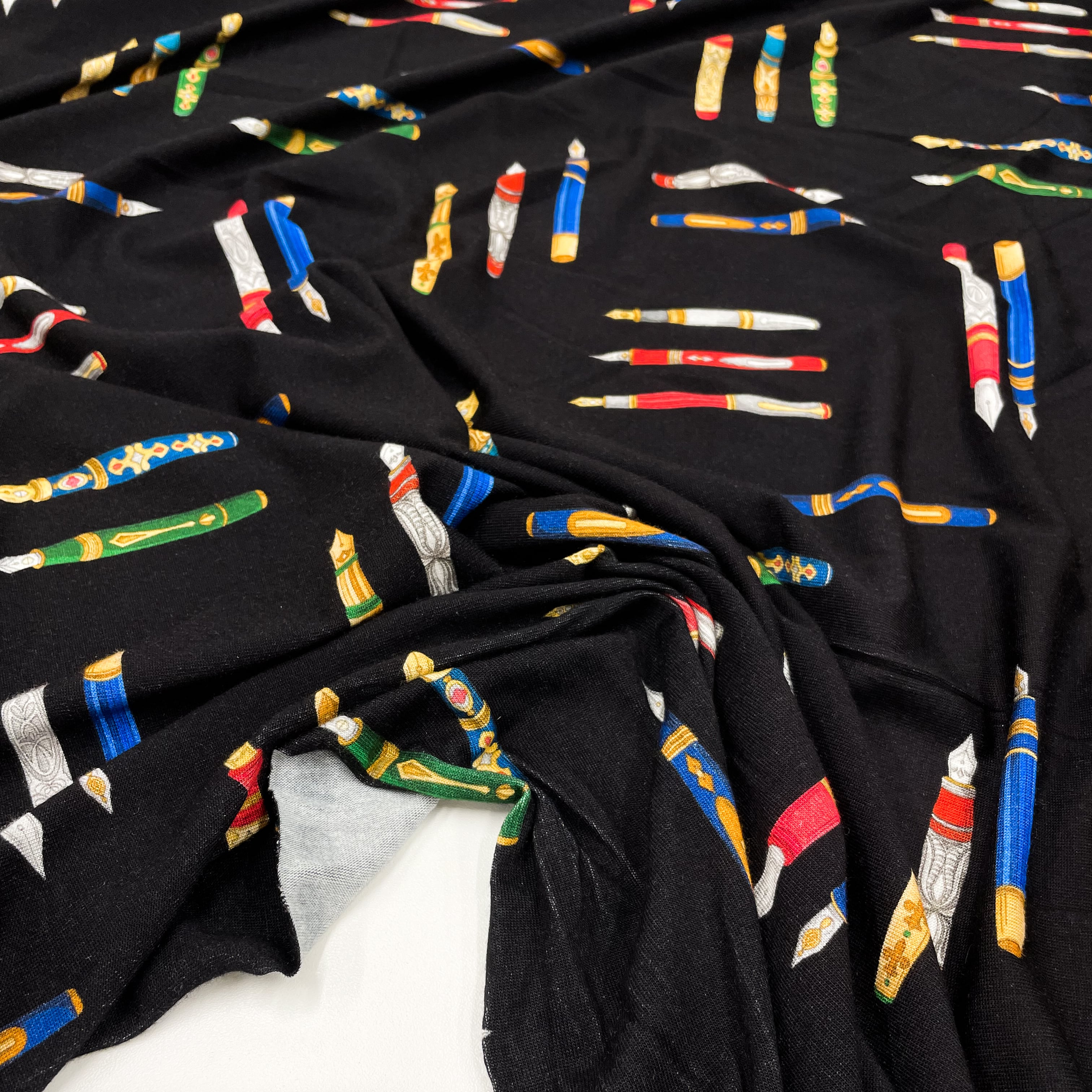 Viscose fabric with pen print on black background, to be found on en.tessuti.fr